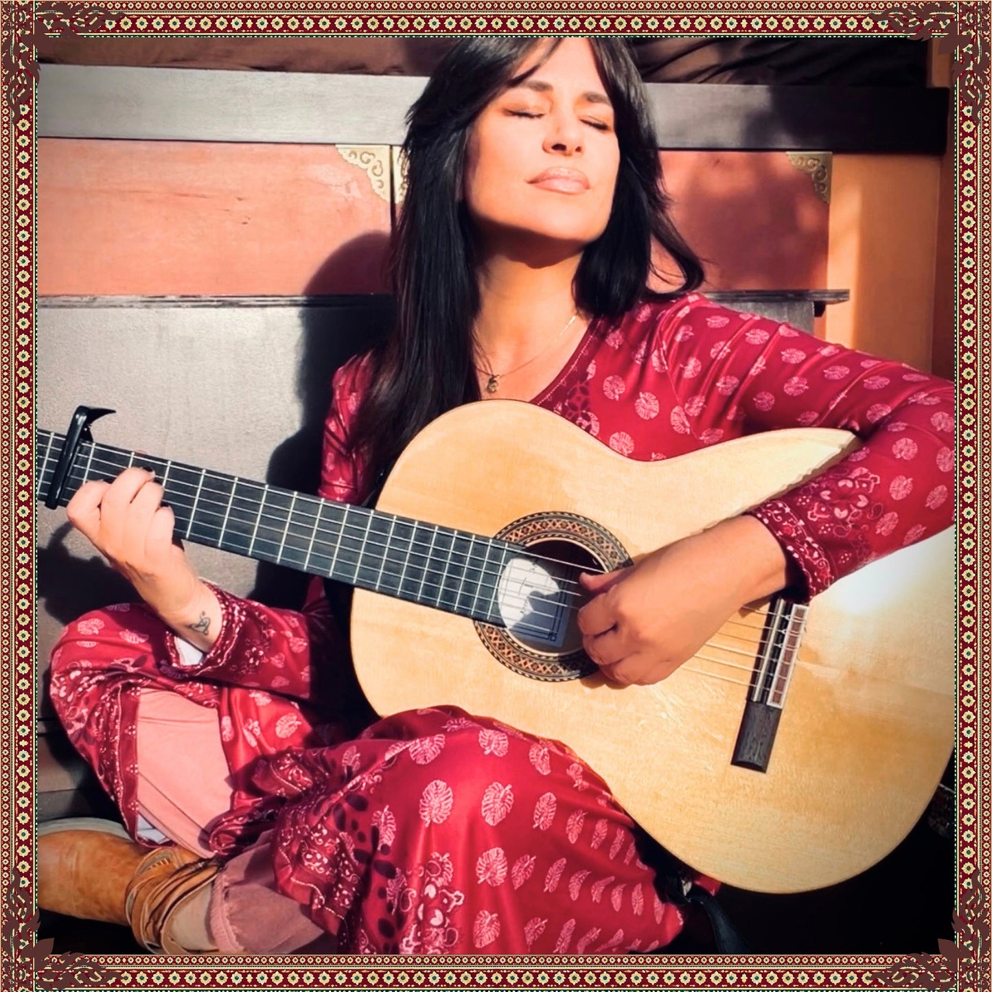 Woman wearing the Rani Rouge Jaipur Kurta Dress by FAVIE while playing a classical guitar, showcasing the flowing red-pink bohemian maxi dress.